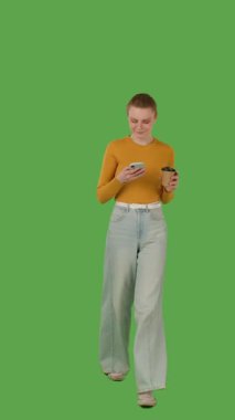 Bir insan yürür ve bir elinde akıllı telefon, diğer elinde bir bardak, yeşil ekranda ise krom anahtar kullanır. Dikey video
