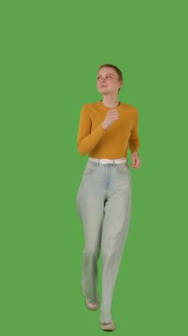 Sarı kazaklı ve geniş paçalı kotlu biri yeşil ekranda koşuyor, kroma anahtarı. Dikey video