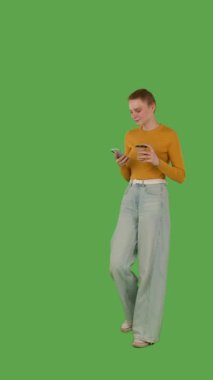 Bir insan yürür ve bir elinde akıllı telefon, diğer elinde bir bardak, yeşil ekranda ise krom anahtar kullanır. Yarım dönüş görünümü, dikey video