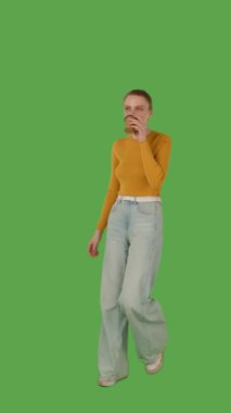 Sarı bluz giyen, elinde fincan tutan, yeşil ekranda yürüyen, krom anahtarı olan biri. Yarım dönüş görünümü, dikey video