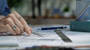 Bir birey, bir masanın üzerinde kesin mimari çizimler yapmak için bir pusula ve cetvel kullanıyor..
