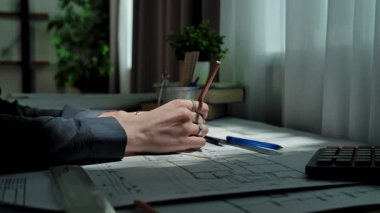 Eller, masa başına odaklanma ve beceriyi yansıtan kalem ve cetvel kullanarak ayrıntılı bir mimari plan çiziyor. Yavaş çekim