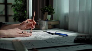 Eller, masa başına odaklanma ve beceriyi yansıtan kalem ve cetvel kullanarak ayrıntılı bir mimari plan çiziyor. Yavaş çekim