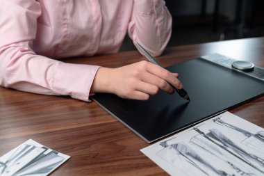 Modern tasarım teknolojisini gösteren dijital grafik tableti kullanan bir kişiyi kapatın..