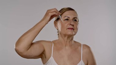 Olgun bir kadın yüz derisini ve canlılığını korumak için deri serumu kullanır..