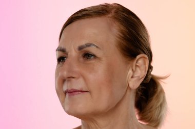 Olgun bir kadının düşünceli yüz ifadesini yaklaştır. Elleri nazikçe yüzünde dinleniyor..