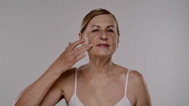 Neşeli bir kadın yaşlanmayı önleyici krem sürerek cilt bakımını besleyici su ve tazelikle arttırır. Yavaş çekim