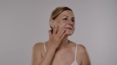 Neşeli bir kadın yaşlanmayı önleyici krem sürerek cilt bakımını besleyici su ve tazelikle arttırır. Yavaş çekim