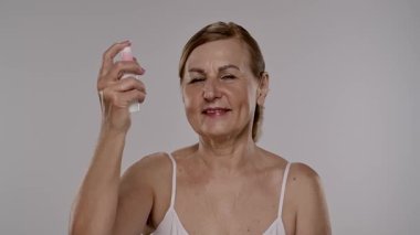 Olgun bir kadın cilt sağlığını ve canlılığını korumak için cilt spreyi kullanır. Yavaş çekim