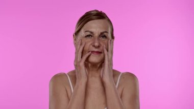 Olgun kadınların düşünceli ifadeleri. Elleri nazikçe yüzünde dinleniyor. Yavaş çekim