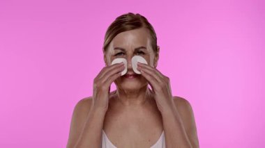 Üst düzey bir kadın yüzünü pamuk pedlerle nazikçe temizliyor, cilt bakımına ve sağlığına odaklanıyor. Yavaş çekim