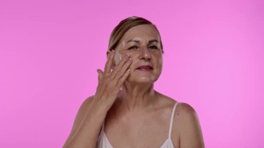 Neşeli bir kadın yaşlanmayı önleyici krem sürerek cilt bakımını besleyici su ve tazelikle arttırır. Yavaş çekim