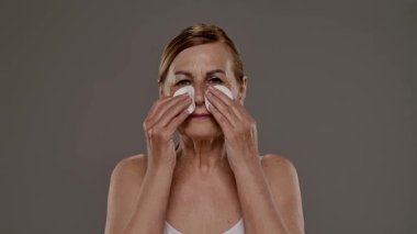 Üst düzey bir kadın yüzünü pamuk pedlerle nazikçe temizliyor, cilt bakımına ve sağlığına odaklanıyor. Yavaş çekim
