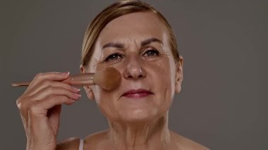 Gecelikli bir kadın yüz silindiri kullanıyor. Bu araç cilt esnekliğini arttırır ve şişkinliği azaltır. Yaklaşın, ağır çekim.