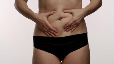 Bir insanın karnını gösteren yakın çekim, öz farkındalığı ve vücut kabulü temalarını vurguluyor. Yavaş çekim