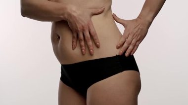 Bir insanın karın derisini çimdiklediği, doku ve yapısına odaklandığı yakın plan bir görüntü. Yavaş çekim