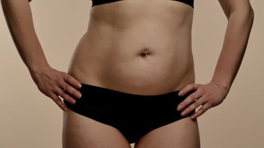 Kapalı çekim bir kadın görüntüsü orta kesimde, siyah iç çamaşırlarıyla düz karnını vurguluyor, yavaş çekim.