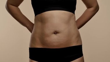 Bir kadın belini bir mezurayla ölçer, spor süreçlerini ve genel sağlık hedeflerini takip etmeye odaklanır. Yaklaşın, ağır çekim.