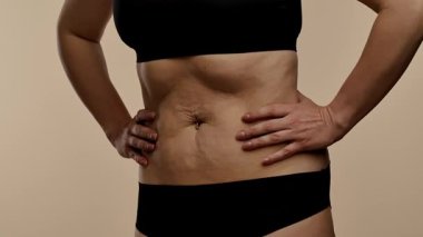 Fotoğrafta siyah iç çamaşırlı bir kadın karnını tutuyor ve karın vakumlama tekniği uyguluyor.