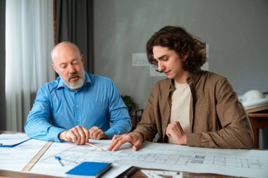 Deneyimli bir mimar akıl hocası genç bir çırak mimari planlar üzerinde çalışırken, işbirliğini teşvik eder..