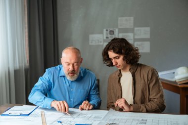 Deneyimli bir mimar akıl hocası genç bir çırak mimari planlar üzerinde çalışırken, işbirliğini teşvik eder..