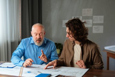Deneyimli bir mimar akıl hocası genç bir çırak mimari planlar üzerinde çalışırken, işbirliğini teşvik eder..