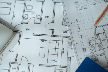 Çalışma alanındaki ahşap bir cetvelin altına yerleştirilmiş detaylı teknik çizimler içeren mimari bir plan..