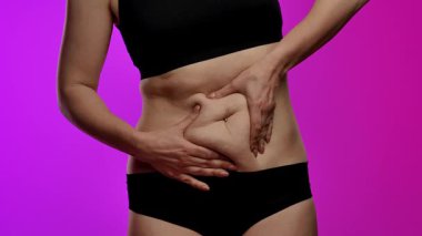 Siyah iç çamaşırı giyen bir kadın midesini tutar. Karın ağrısı ya da ağrı göstergesi olabilir. Yaklaşın, ağır çekim.