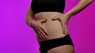 Bir insanın karın derisini çimdiklediği, doku ve yapısına odaklandığı yakın plan bir görüntü. Yavaş çekim