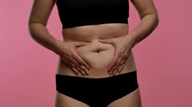 Siyah iç çamaşırı giyen bir kadın midesini tutar. Karın ağrısı ya da ağrı göstergesi olabilir. Yaklaşın, ağır çekim.