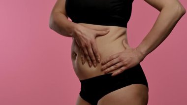 Bir insanın karın derisini çimdiklediği, doku ve yapısına odaklandığı yakın plan bir görüntü. Yavaş çekim