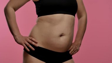 Orta kısımda siyah iç çamaşırlarıyla karnını aydınlatan bir kadının yakın çekim görüntüsü. Yavaş çekim