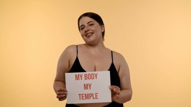 Bir kadın güçlü bir iç çekiş yapıyor Vücudum Tapınağım vücudum pozitifliği destekleyici bir ortamda kişisel gücü ve sevgiyi vurguluyor..