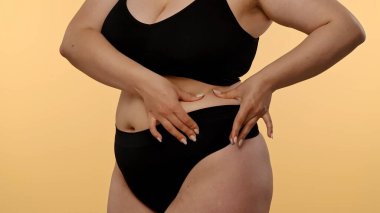 Kişilerin karnını gösteren, kendi farkındalığını ve vücut kabulünü vurgulayan bir görünüm.