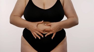 Kişilerin karnını gösteren, kendi farkındalığını ve vücut kabulünü vurgulayan bir görünüm.