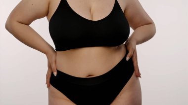 Kendine güvenen, kıvrımlı bir kadın zarif ve rahat siyah iç çamaşırlarıyla vücuduna karşı olumlu bir tavır sergilerken....