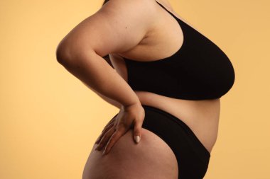 Sanatsal açıdan siyah iç çamaşırlı bir kadının doğal vücut kıvrımlarını ve deri dokusunu vurgulaması. Yan görünüm