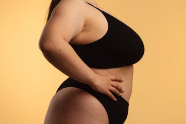 Sanatsal açıdan siyah iç çamaşırlı bir kadının doğal vücut kıvrımlarını ve deri dokusunu vurgulaması. Yan görünüm