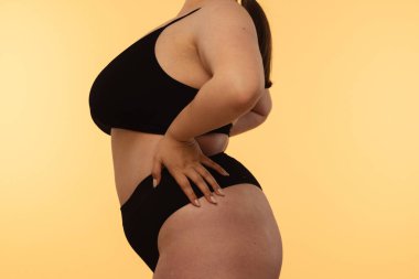 Sanatsal açıdan siyah iç çamaşırlı bir kadının doğal vücut kıvrımlarını ve deri dokusunu vurgulaması. Yan görünüm