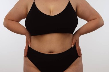 Kendine güvenen, kıvrımlı bir kadın zarif ve rahat siyah iç çamaşırlarıyla vücuduna karşı olumlu bir tavır sergilerken....