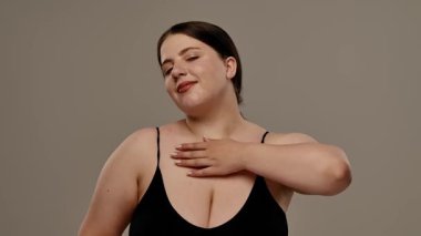 Siyah bluzlu bir kadın tarafsız bir geçmişle güvenle gülümsüyor, basitlik ve zarafet taşıyor. Yavaş çekim