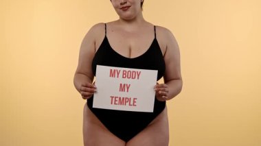 Bir kadın güçlü bir iç çekiş yapıyor Vücudum Tapınağım vücudum pozitifliğini destekliyor, kişisel sevgiyi ve kişisel yetkiyi destekleyici bir ortamda vurguluyor. Yavaş çekim