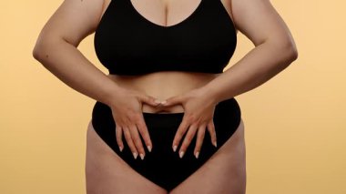 Görüntüde, göbeğinde kalp şekli oluşturan bir kadın var. Tarafsız bir arkaplana karşı aşkı ya da sağlık bilincini simgeliyor. Yavaş çekim