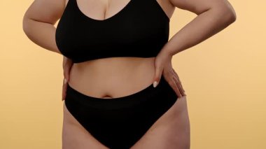 Kendine güvenen, kıvrımlı bir kadın zarif ve rahat siyah iç çamaşırlarıyla vücuduna karşı olumlu bir tavır sergilerken stilini sergiler. Yavaş çekim