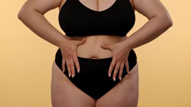 Kişilerin karnını gösteren, özfarkındalığı ve vücut kabulü temalarını vurgulayan bir manzara. Yavaş çekim