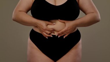 Kişilerin karnını gösteren, özfarkındalığı ve vücut kabulü temalarını vurgulayan bir manzara. Yavaş çekim