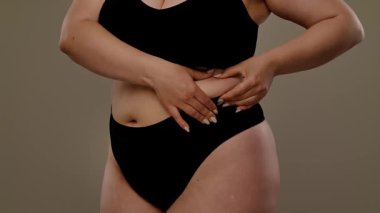 Karın derisini çimdikleyen bir kişinin görüntüsü, yapısına ve dokusuna odaklanıyor. Yavaş çekim