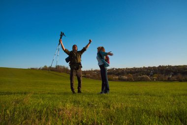 Neşeli bir çift kırsalda güneşli bir günde yürüyüş yaparken doğayı kucaklıyor, özgürlüğü kutluyor..