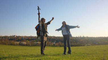 Neşeli bir çift kırsalda güneşli bir günde yürüyüş yaparken doğayı kucaklıyor, özgürlüğü kutluyor..