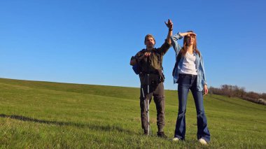 İki insan açık, engin bir alanı keşfeder açık mavi gökyüzünün altında, doğayı ve macera ruhunu kucaklayarak..